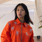 Orange embroidered shirt with floral detailing styled in a contemporary outdoor setting