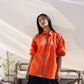 Orange embroidered shirt with floral detailing styled in a contemporary outdoor setting