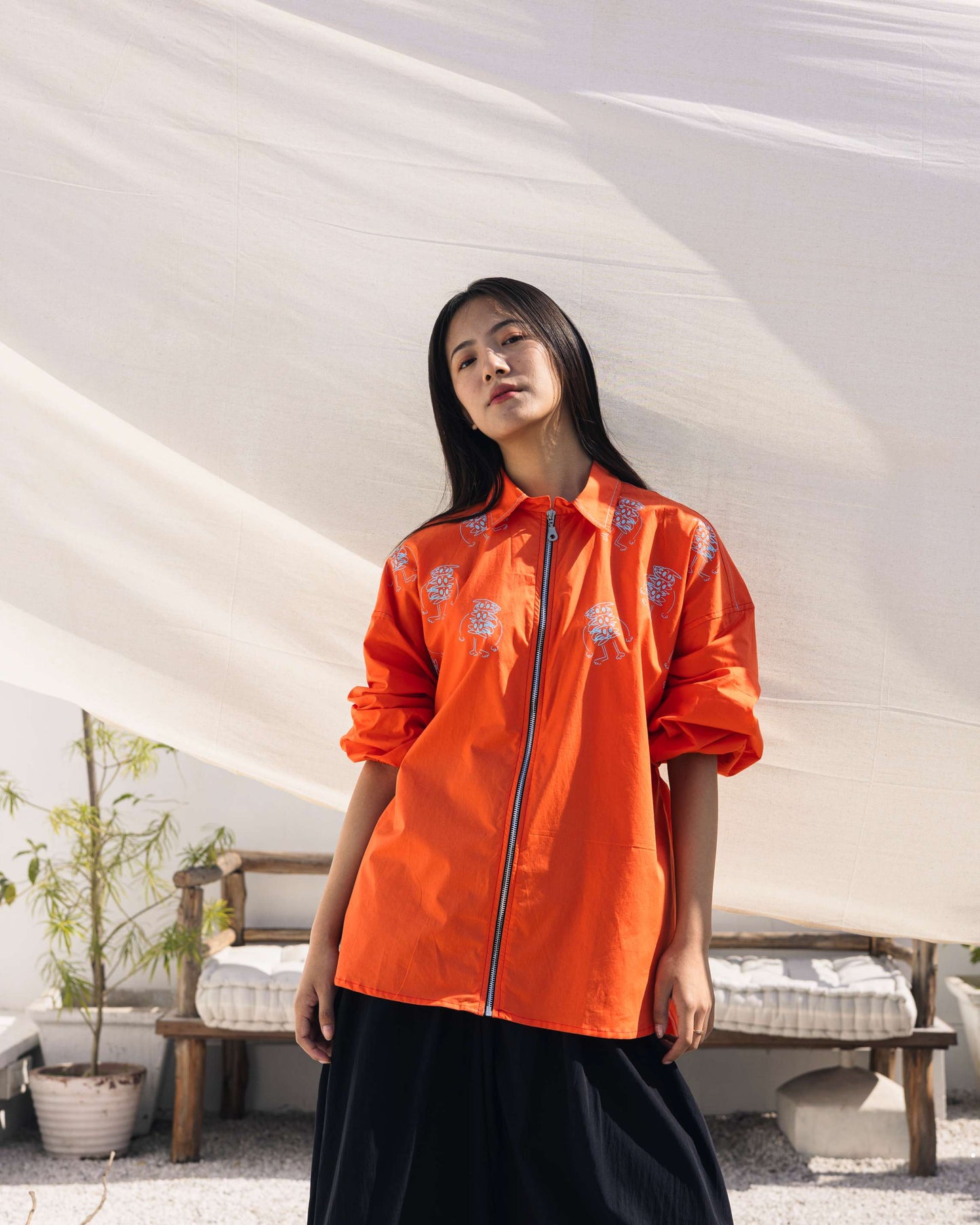 Orange embroidered shirt with floral detailing styled in a contemporary outdoor setting