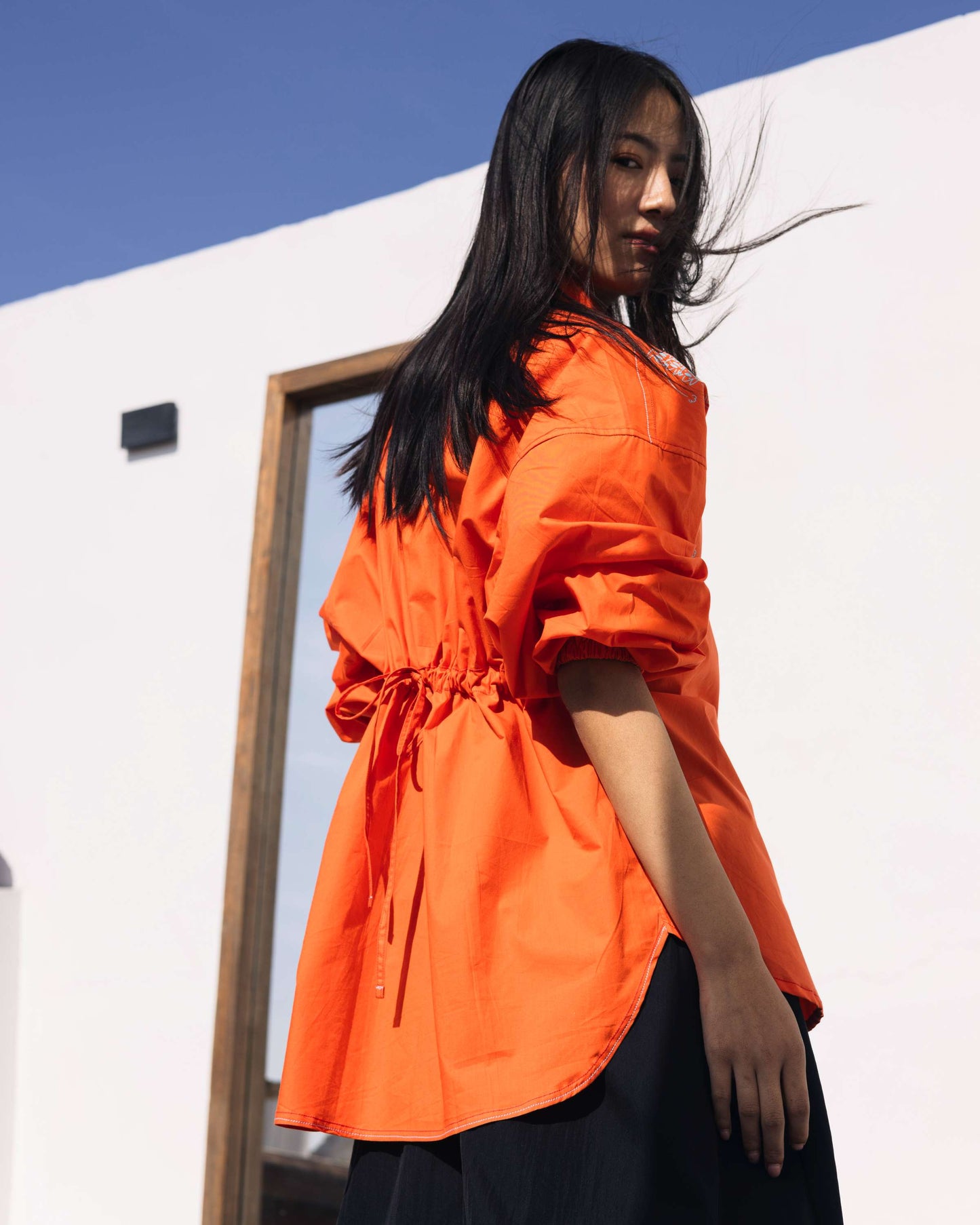 Orange embroidered shirt with floral detailing styled in a contemporary outdoor setting